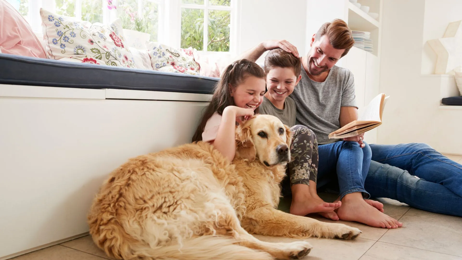 A father and children reading together at home with their golden retriever